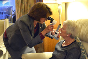 Barbara Watson carrying out an eye test on an elderly lady in their own home