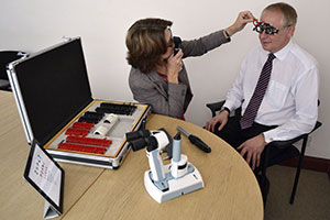 home page image no 3 showing Barbara Watson conducting an eye test in a company office